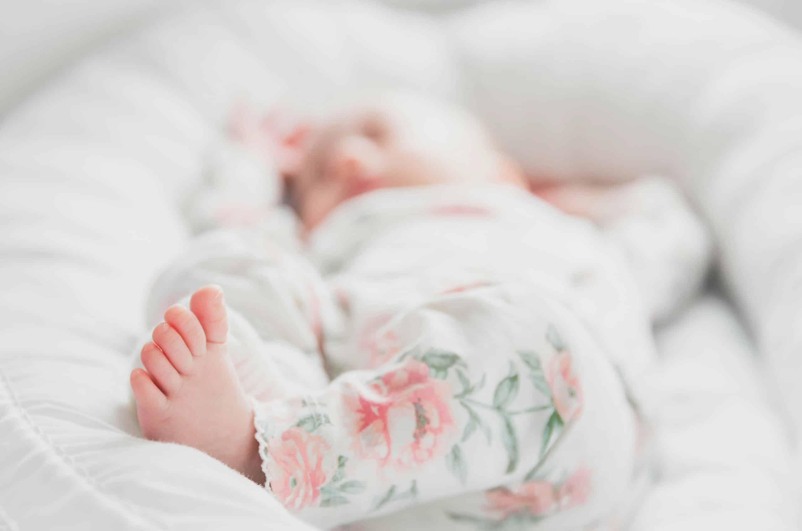 Infant sleeping peacefully in a white nest lounger representing newborn care specialist services